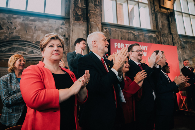 Gruppe von Menschen, die vor einer Menge jubeln, mit einem Banner mit der Aufschrift "Wahlsieg" im Hintergrund
