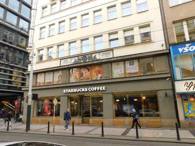 Ein Starbucks-Café an einer Straßenecke in Berlin, Deutschland, mit Passanten, einem Auto, Strommasten und Schildern am Gebäude.