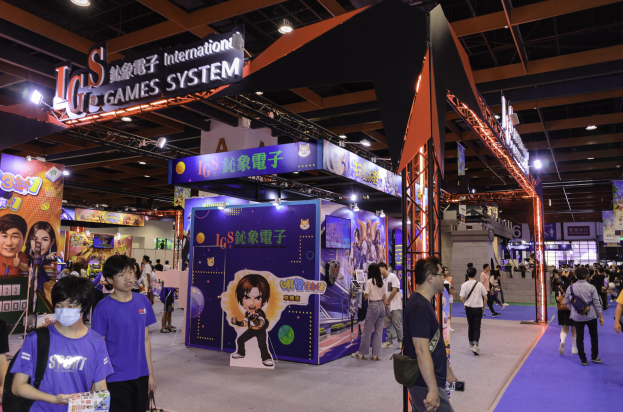 Eine Gruppe von Menschen durchquert einen Convention-Saal auf einer Gaming-Messe in China, einige tragen Taschen und halten Gegenstände, mit Informationsplakaten, Deckenleuchten und einem Teppichboden.