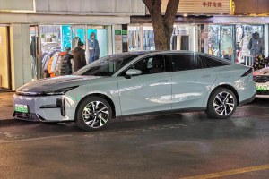 Ein Mitsubishi Lancer EV auf einer Straße bei Nacht, umgeben von Gebäuden, Geschäften, Schaufensterpuppen, Schildern und Lichtern.
