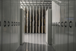 Ein großer Raum voller numerous metalen Schließfächer, ein Boden, eine Decke mit Stangen und verschiedene Gegenstände im Hintergrund, die wie ein Rechenzentrum aussehen.