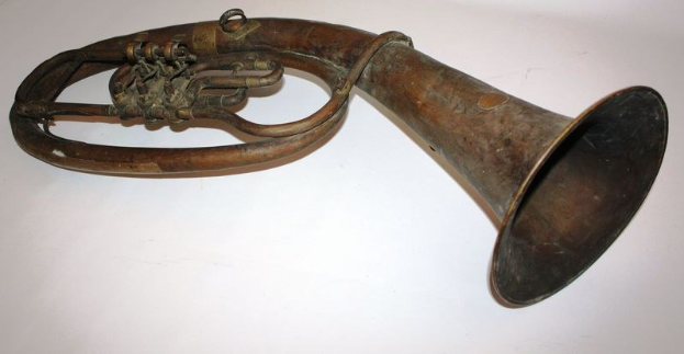 Alter Messinghorn mit glänzendem Finish, gebogenem Hals und aufgeblasenem Schalltrichter, verziert mit kunstvollen Gravuren, auf einem weißen Hintergrund.