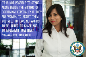 Eine Frau in einem weißen Hemd steht vor einem Gebäude, auf dem ein Zitat zum Thema Unterstützung von Opfern des Extremismus steht, mit einem Logo in der rechten unteren Ecke.