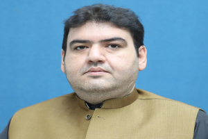 Ein Mann in brauner Weste und schwarzem Hemd steht vor einem blauen Hintergrund und sieht besorgt, traurig und hoffnungslos aus, wahrscheinlich wegen einer lebenslangen Haftstrafe.