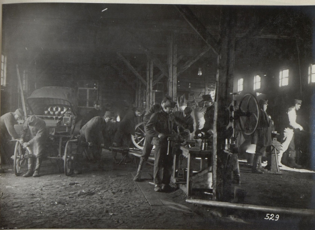 Schwarzes und weißes Bild von Männern, die in einer Fabrik arbeiten, mit einem Fahrzeug und Fenstern im Hintergrund.