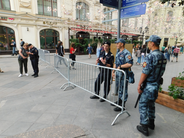 Polizeibeamte in Uniform stehen hinter Barrieren und schauen auf eine Menge, einige halten Waffen, mit Gebäuden und Bäumen im Hintergrund während einer Anti-Terror-Operation in Wien, Österreich.