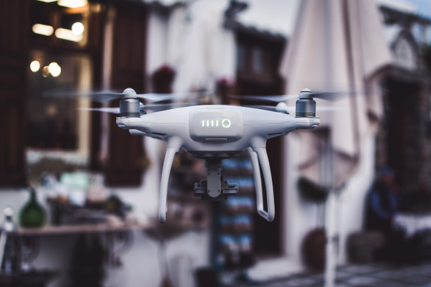 Weißer DJI Phantom 3 Advanced Drohne im Flug gegen einen unscharfen städtischen Hintergrund.