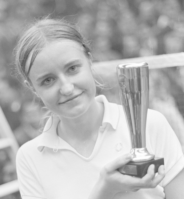 Eine Frau, die strahlend eine Trophäe hält, mit einem leicht unscharfen Hintergrund.