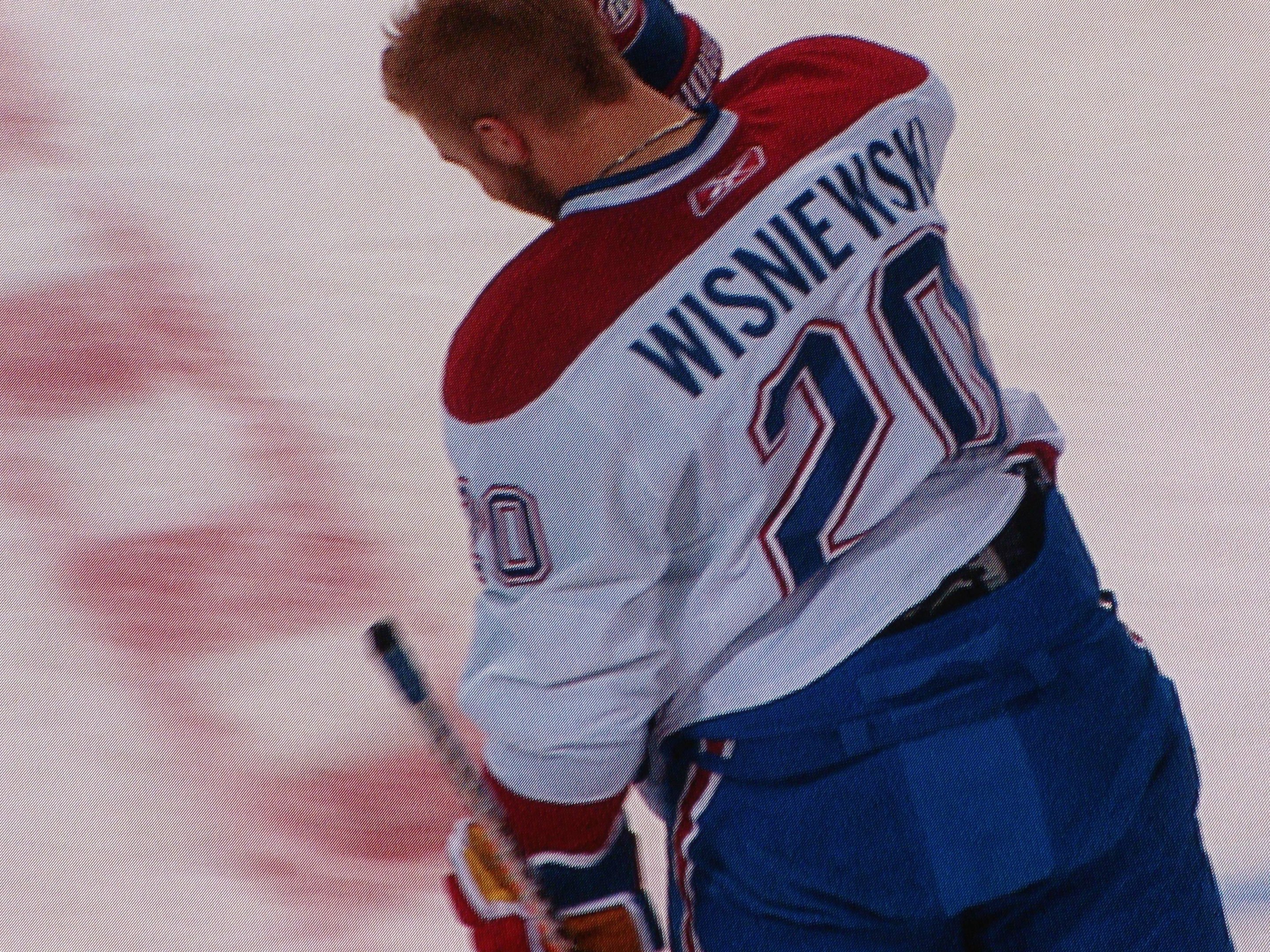 Professioneller Eishockeyspieler in einem "Wisniewski"-Trikot, der einen Eishockeyschläger auf dem Eis hält und konzentriert schaut.