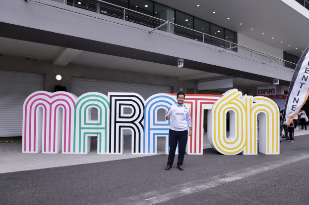 Ein Mann, der vor einem "Marathon"-Schild lächelt, umgeben von Menschen mit Schildern, vor einem beleuchteten Gebäude
