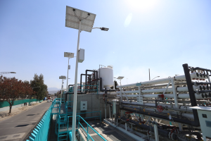 Großes industrielles Gebäude mit umfangreichen Rohrleitungen, Solarmodulen, Geländern und Infrastruktur, umgeben von Hügeln unter einem klaren blauen Himmel, Teil der neuen Wasseraufbereitungsanlage von Kalifornien.