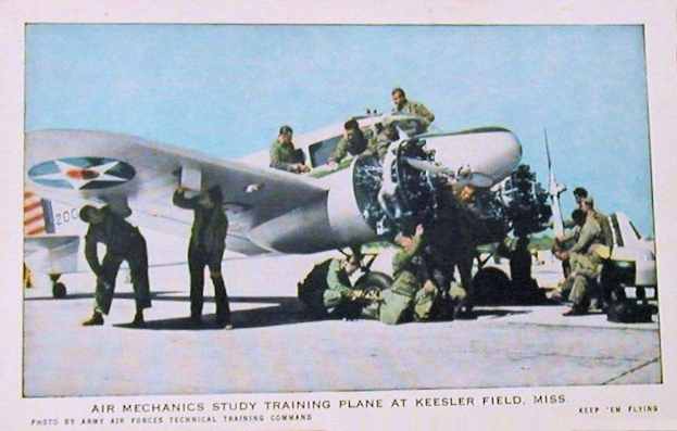 Gruppe von Menschen um ein Trainingsflugzeug auf einer Landebahn mit einem klaren blauen Himmel, Text unten lautet "Luftfahrzeugmechaniker-Ausbildungsflugzeug auf Keesler Field, Miss."