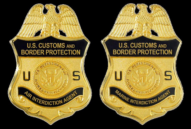 Zwei goldfarbene Abzeichen mit 'U.S. Customs and Border Protection'-Text auf weißem Hintergrund.