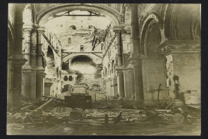 Ein altes Schwarz-Weiß-Foto eines zerstörten Kircheninneren mit zerbrochenem Holz auf dem Boden und Säulen und Bögen im Hintergrund.